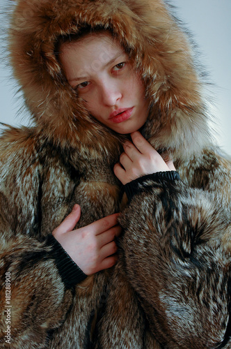 Young beautiful girl shows the photographer part of her young body. A wolfskin jacket. photo