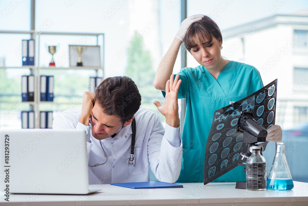 Two doctors discussing x-ray MRI image in hospital Two doctors discussing x-ray MRI image in hospital