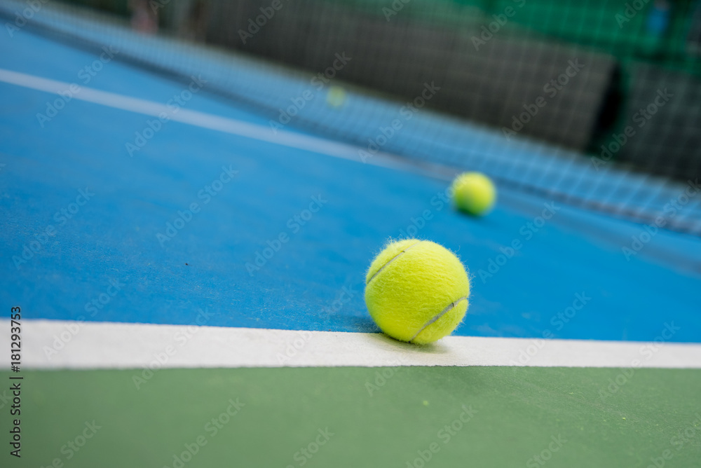Yellow tennis ball on blue and green hard court surface 