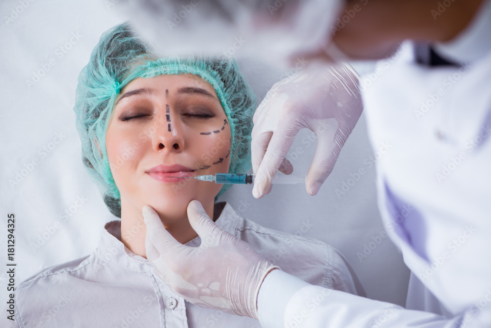 Naklejka premium Plastic surgeon preparing for operation on woman face