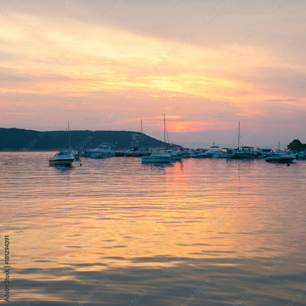 The fiery sunset reflects on the sea of  the marina.