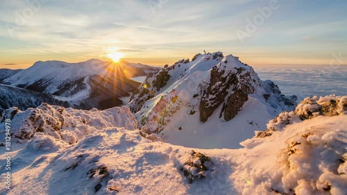 Colorful golden sunset in snowy mountains in winter above mist clouds. Dolly shot time lapse day to night
