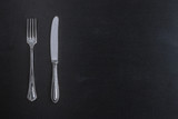 Fork and knife cutlery on black chalkboard background top view top view template for menu