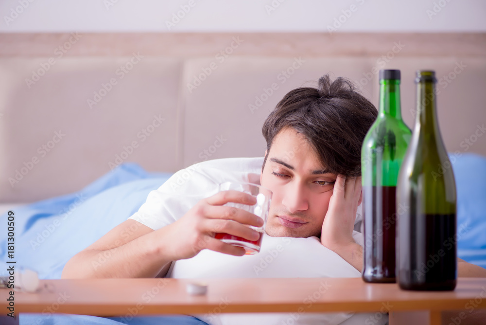 Man alcoholic drinking in bed going through break up depression Man alcoholic drinking in bed going through break up depression