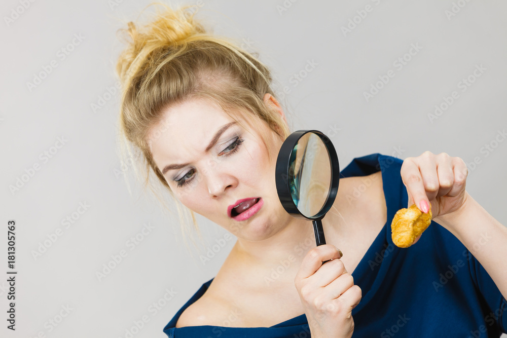 Woman holding magnifying glass investigating bread Woman holding magnifying glass investigating bread