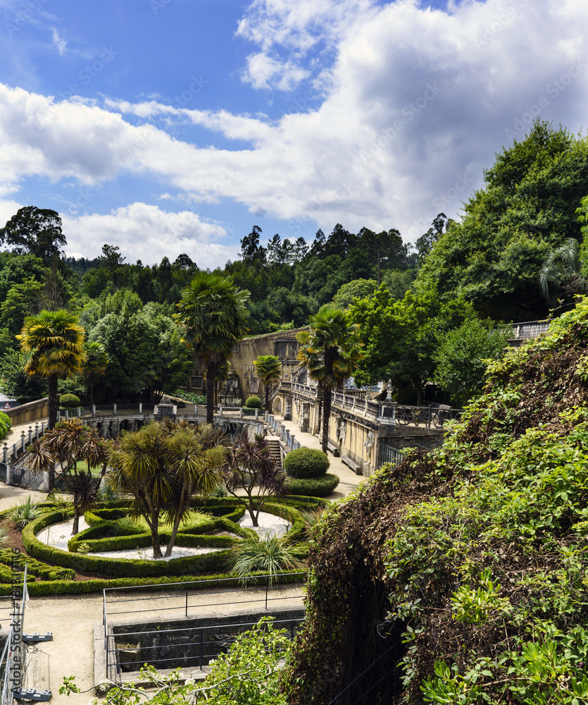 Old artistic buildings in a very green and leafy area, with a sky with clouds. Park of the brothers Naveira in Betanzos, Galicia, Spain