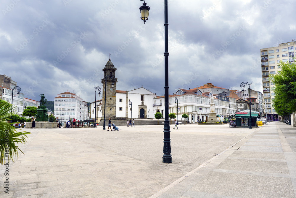 betanzos, Galicia, Spain. July 30, 2017: Main square of the town with people walking and a kiosk selling magazines. In the background the village church