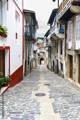 Typical street of a village of galicia on slope and finished in an arch with the stone floor and old houses in a village called Betanzos in Galicia, Spain