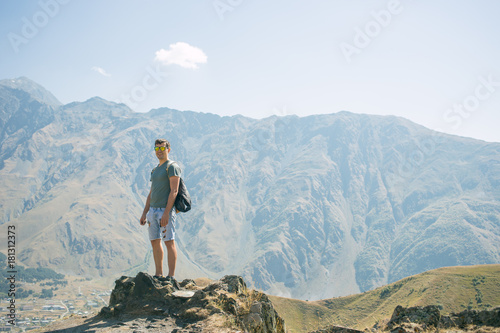 Guy with a travel backpack on the top of a boulder