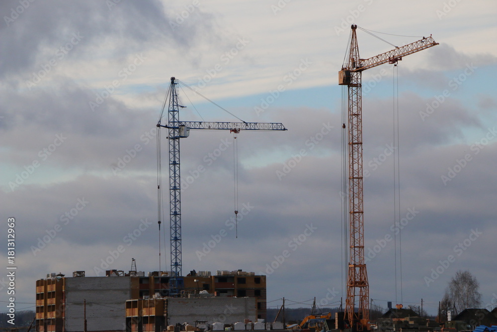 construction of high-rise residential building in the field with the help of several tower high cranes in the autumn season