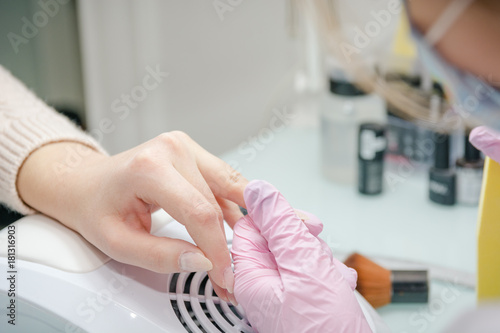 Processing of nails. The girl grinds off nails in beauty shop.