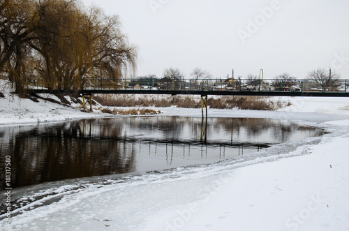 Footbridge across the frozen river © ihorbondarenko