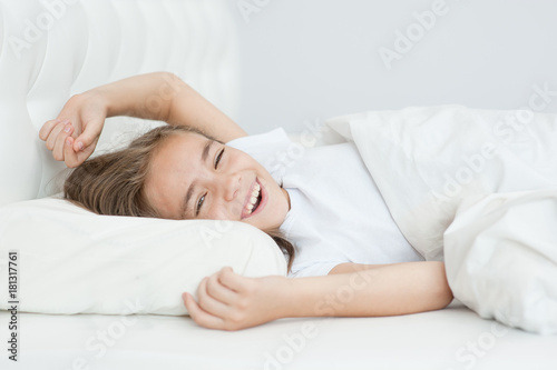 Happy girl stretching in bed after wake up