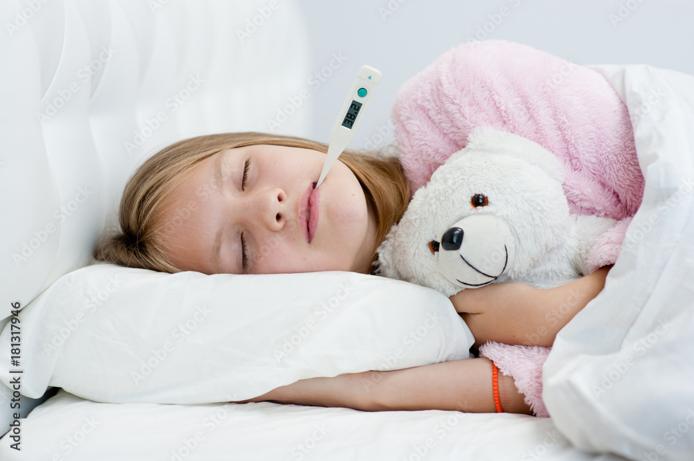 sick girl with toy bear lying in bed with a thermometer in mouth sick girl with toy bear lying in bed with a thermometer in mouth
