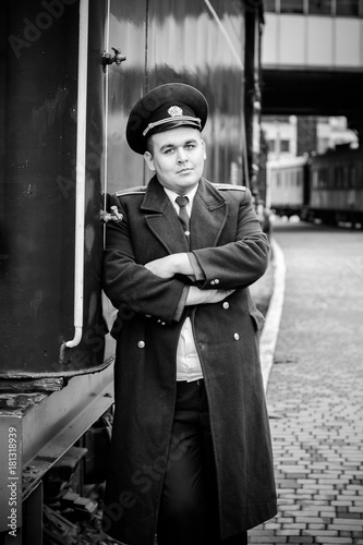 European or American train conductor is on his duty on a platform and other trains. Railway, steam trains, vintage trains photo