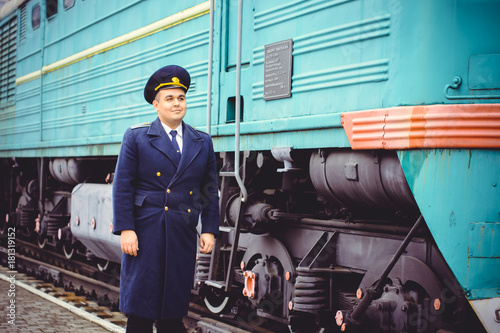 European or American train conductor is on his duty on a platform and other trains. Railway, steam trains, vintage trains