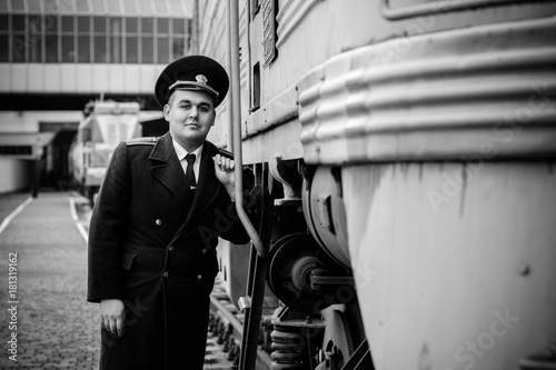 European or American train conductor is on his duty on a platform and other trains. Railway, steam trains, vintage trains photo