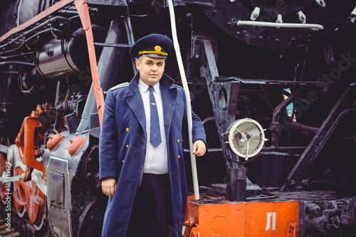 European or American train conductor is on his duty on a platform and other trains. Railway, steam trains, vintage trains photo