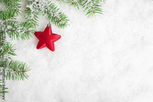 Snowy fir branches with christmas red star over snow. Christmas and New Year Background with copy space.