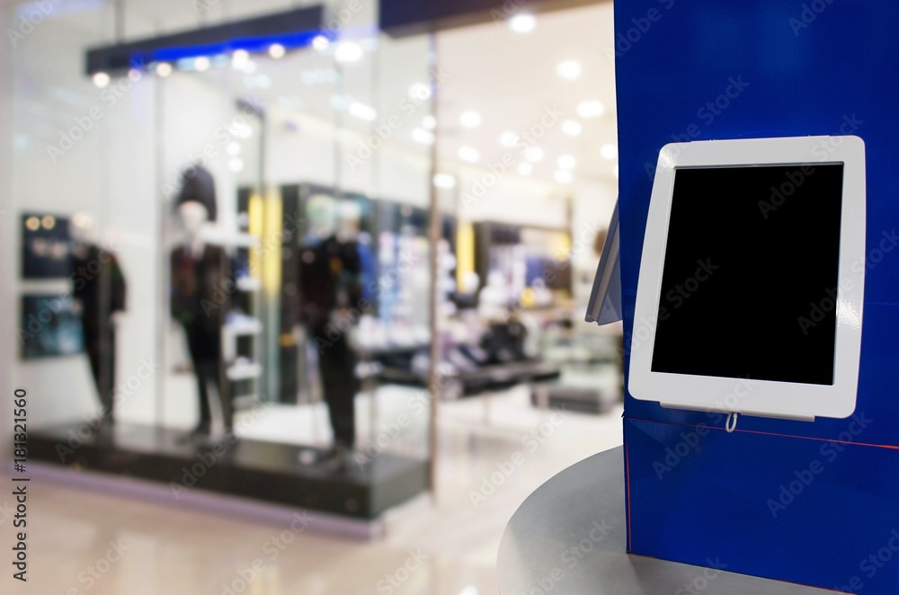 blank digital monitor or tablet on counter in front of men fashion clothes  shop showcase in department store shopping mall, copy space for text or  media content, marketing, advertisement concept Stock Photo