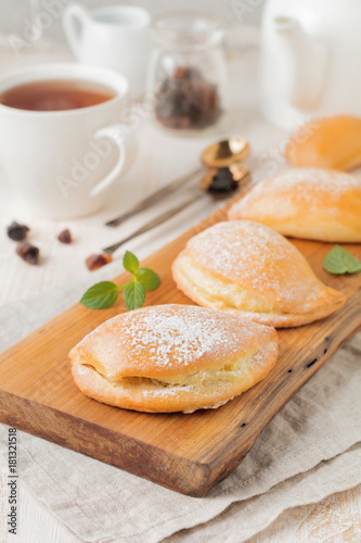 Pasties with cottage cheese and powdered sugar on a light wooden background. Traditional Russian pastry Sochnik. Selective focus. .