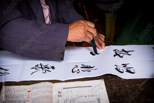 Man is writing with chinese idioms at  Shigu Village or Stone Drum Village, Lijiang, Yunnan Province, China, Asia, Asian, East Asia, Far East photo