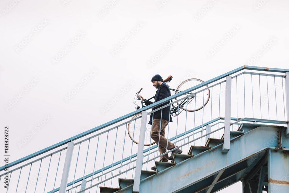 Hipster man carry bicycle down the stairs