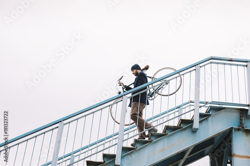 Hipster man carry bicycle down the stairs