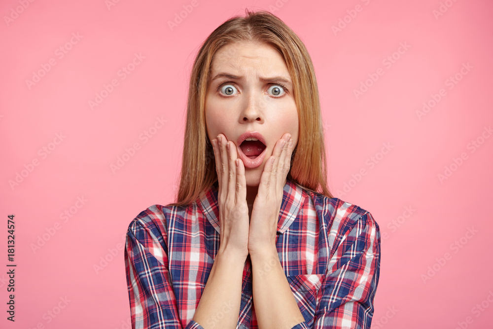 Portrait of emotional young attractive female looks surprisedly at camera, being shocked to hear awful news, can`t believe her eyes, stupefied and in stupor, afraid of difficulties. Excitement concept Portrait of emotional young attractive female looks surprisedly at camera, being shocked to hear awful news, can`t believe her eyes, stupefied and in stupor, afraid of difficulties. Excitement concept