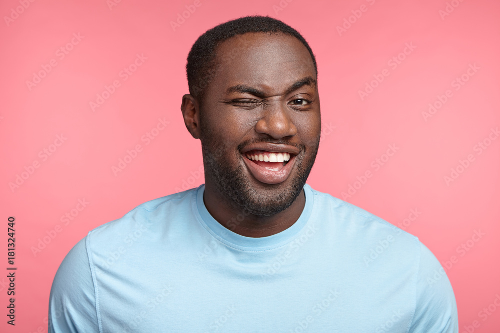 Cheerful plump middle aged dark skinned man blinks eye and has appealing  smile, flirts with beautiful woman who stands before, tells jokes or funny  stories, isolated over pink studio background. Stock Photo |