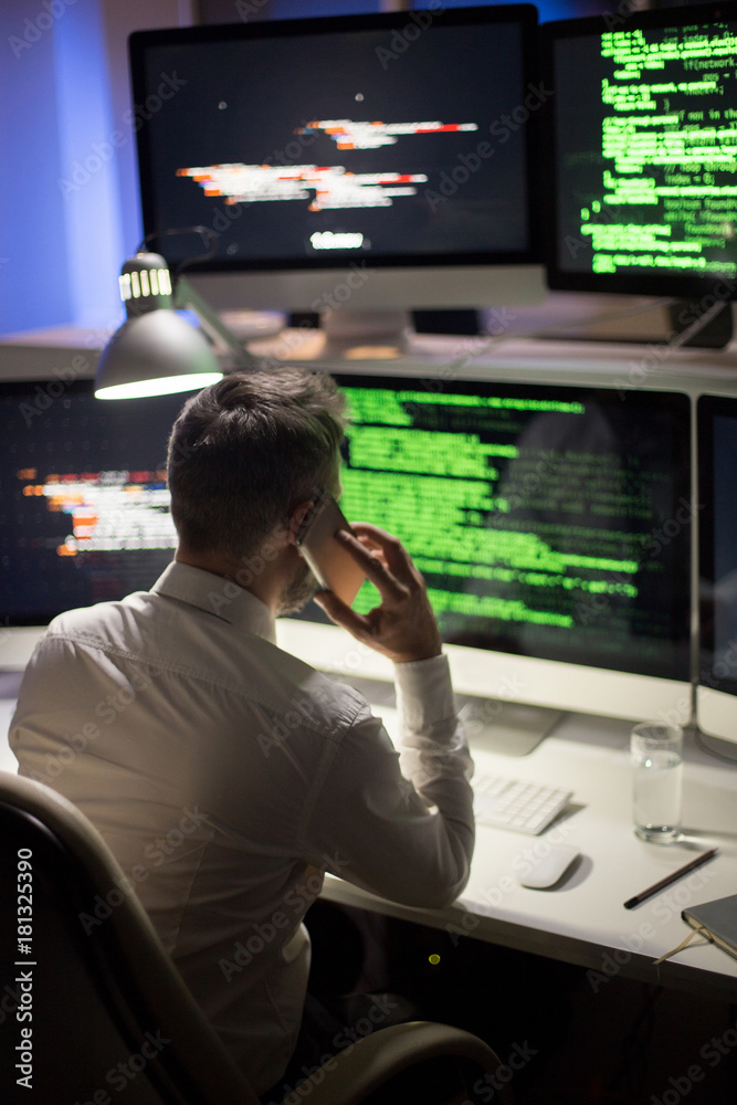Back view of unrecognizable programmer wearing white shirt sitting in ...
