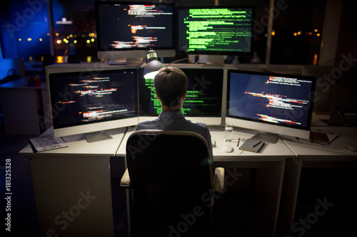 Fotografie Rear view of hard-working programmer with stylish haircut sitting in front of co