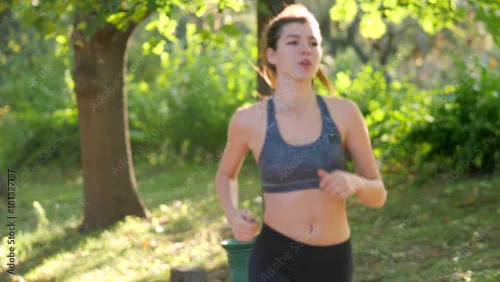 Young woman is running through the park on a sunny summer day Young woman is running through the park on a sunny summer day