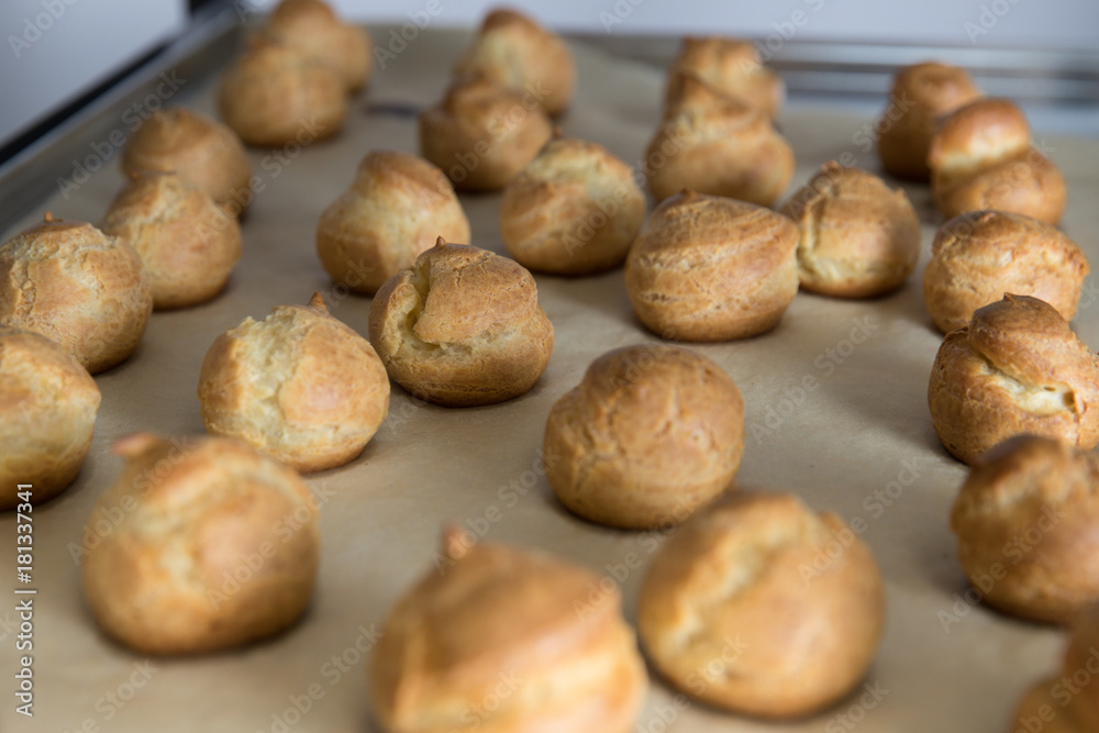 French dessert profiterole cake or eclair are on the baking paper French dessert profiterole cake or eclair are on the baking paper
