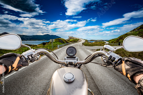Biker rides a road with Atlantic Ocean Road in Norway. First-person view.