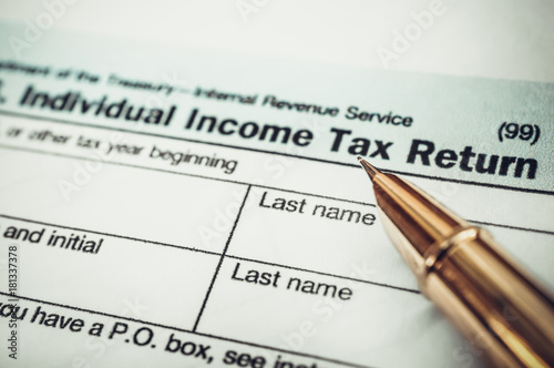 Pen pointing on word "tax" on the tax form. Close up. Business concept. Toned image.