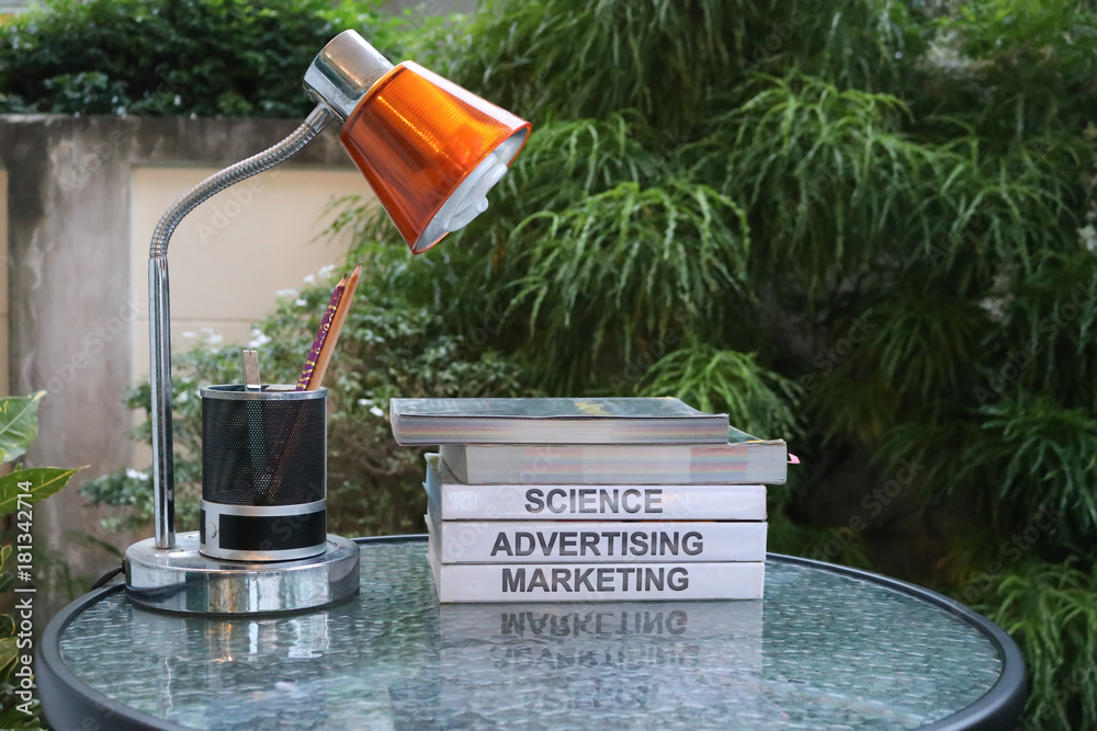 Fototapeta premium Several textbooks on glass table with table lamp