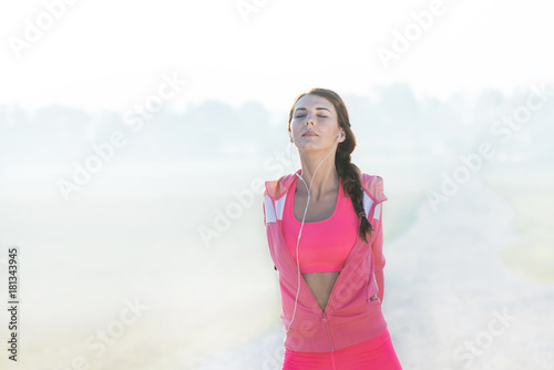 amazing female athlete model wearing pink clothes streching just before the start of a running workout early in the morning