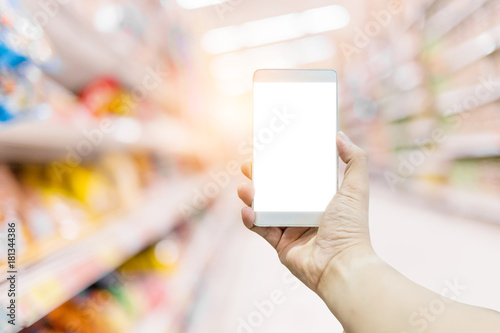 hand and smartphone with Supermarket blurred background with bokeh