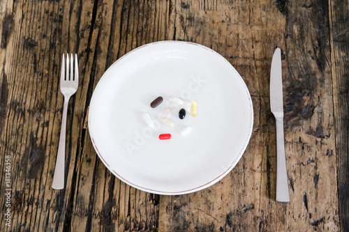 different color pills with a plate setting symbolizing futuristic space age food and supplements photo