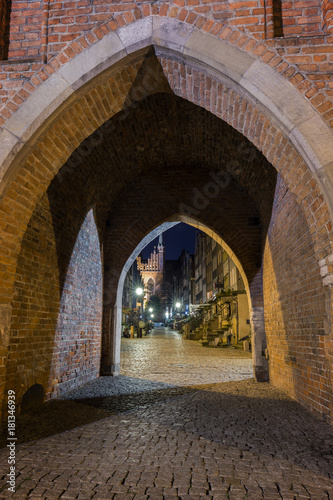 Old buildings on the St. Mary s Street  ul. Mariacka  and St. Mary s Church at the Main Town  Old Town  in Gdansk  Poland  viewed through an arched gateway in the evening.