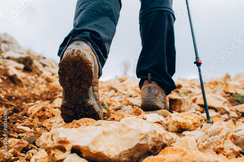 Close-up trekking shoes, bottom view. Man hiking in mountain on rocky path. Active outdoor recreation