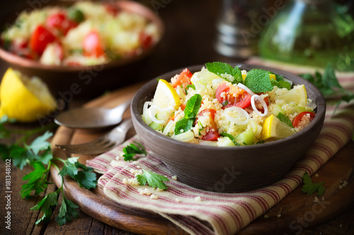 Fototapeta Naklejka Na Ścianę i Meble -  Vegetarian tabbouleh - delicious couscous salad with cherry tomatoes, cucumbers, fresh mint and parsley leaves.