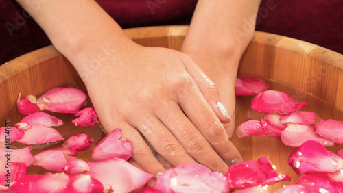 Close up of a female hands with bowl of aroma spa water and pink rose petal.
