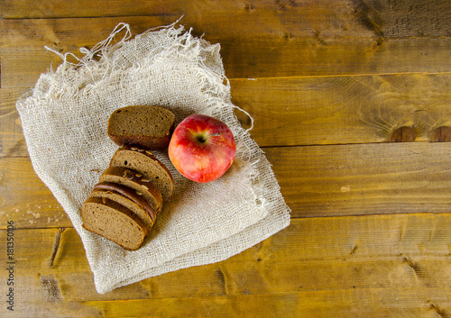 a few pieces of bread and an apple on a burlap on a wooden surface