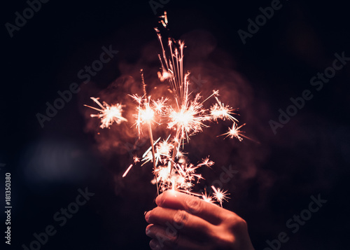 Canvas Print Hand holding burning Sparkler blast on a black background at night,holiday celebration event party,dark vintage tone