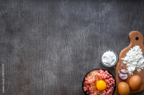 Raw minced meat with egg yolk, wooden cutting board on wooden background