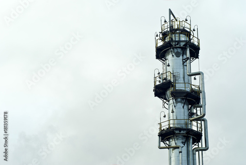 Photos the upper part of a shiny gigantic metal fractionating column at a chemical or r