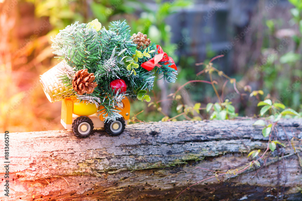 Miniature of lorry transportation toy with Christmas tree in blurred nature background. Holidays concept.
