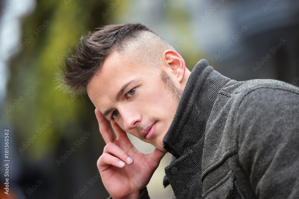young man thinking while sitting on a bench in autumn young man thinking while sitting on a bench in autumn